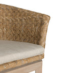 KULALA Living handwoven rattan dining chair with a curved backrest, natural wood legs, and a neutral seat cushion, blending coastal and contemporary design