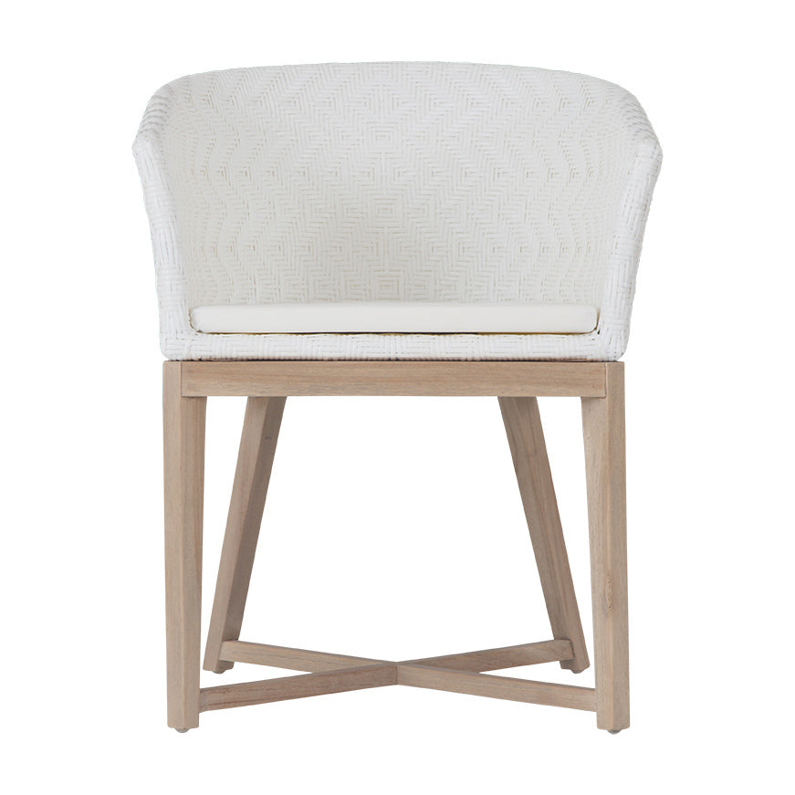 KULALA Living handwoven rattan dining chair with a curved backrest, natural wood legs, and a white seat cushion, blending coastal and contemporary design