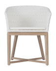 KULALA Living handwoven rattan dining chair with a curved backrest, natural wood legs, and a white seat cushion, blending coastal and contemporary design