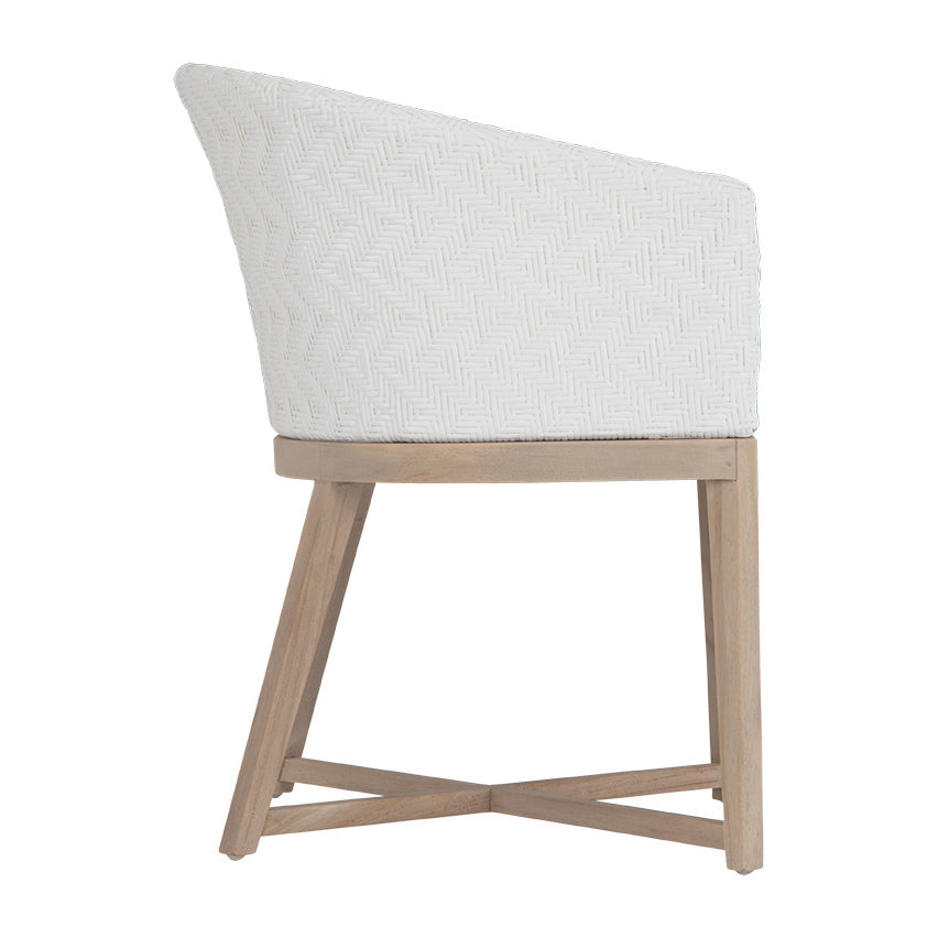 KULALA Living handwoven rattan dining chair with a curved backrest, natural wood legs, and a white seat cushion, blending coastal and contemporary design