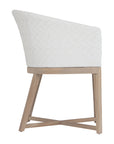 KULALA Living handwoven rattan dining chair with a curved backrest, natural wood legs, and a white seat cushion, blending coastal and contemporary design