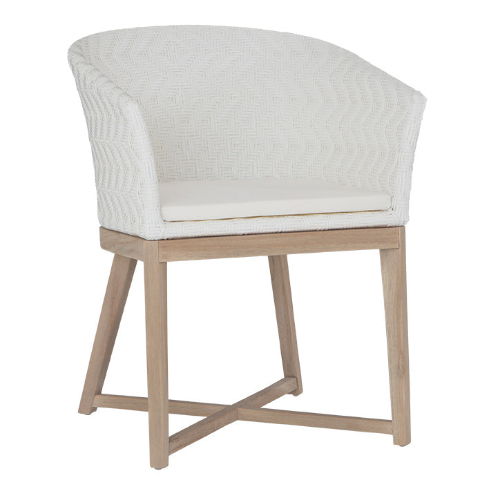 KULALA Living handwoven rattan dining chair with a curved backrest, natural wood legs, and a white seat cushion, blending coastal and contemporary design