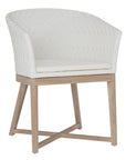 KULALA Living handwoven rattan dining chair with a curved backrest, natural wood legs, and a white seat cushion, blending coastal and contemporary design